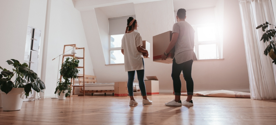 Two people holding boxes in an empty house